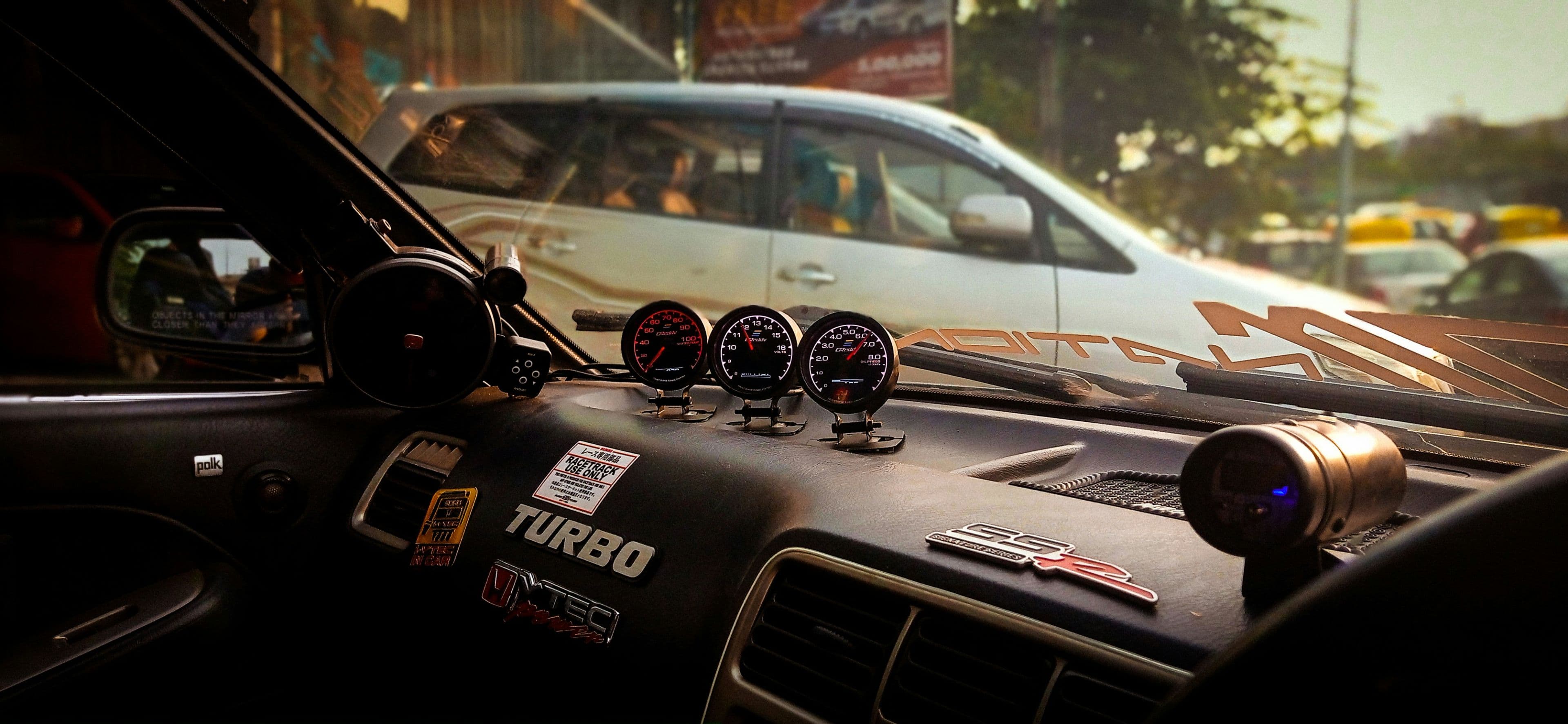 A power inverter plugged into a car's dashboard socket charging a laptop