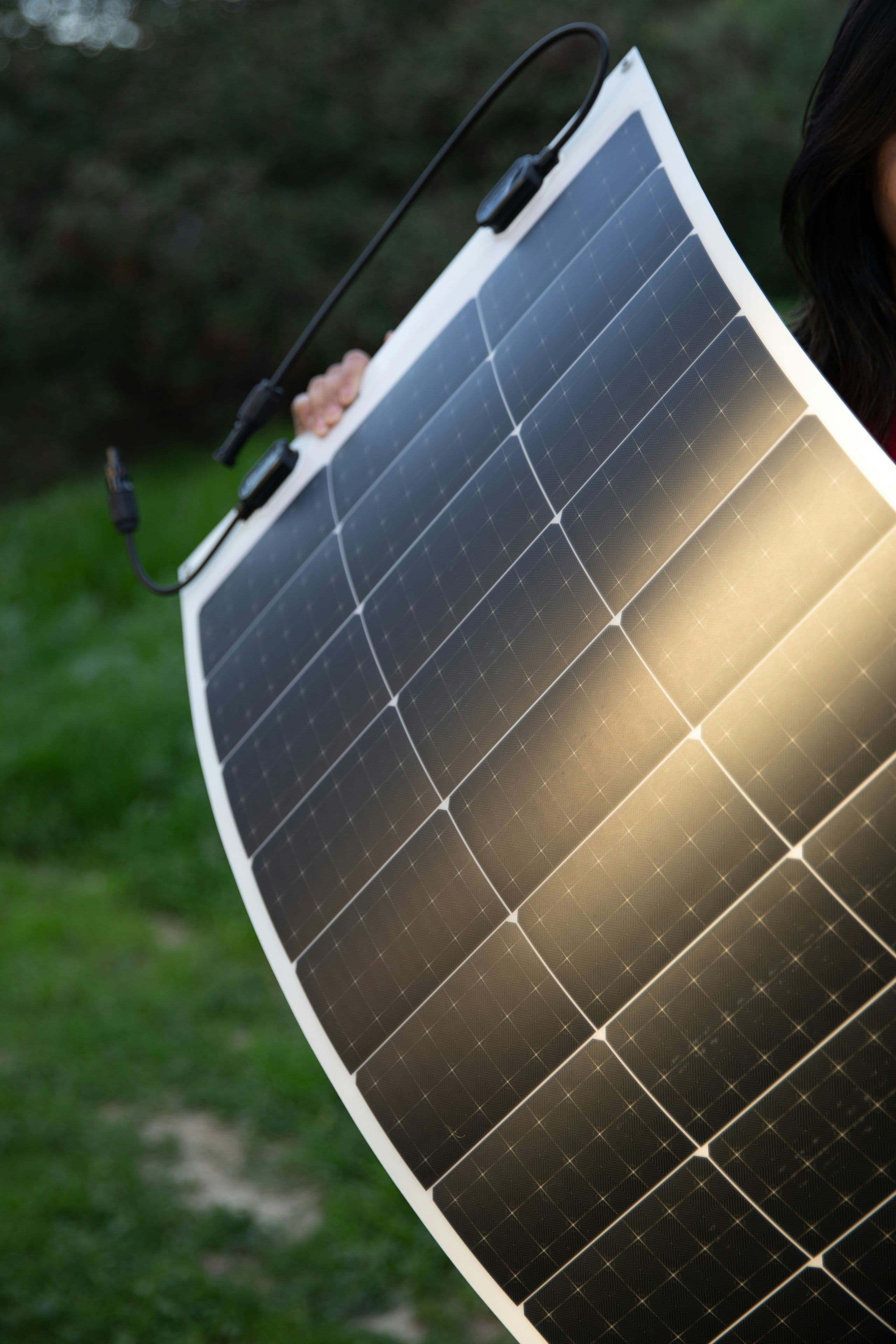 A folding portable solar panel angled toward the sun on grass