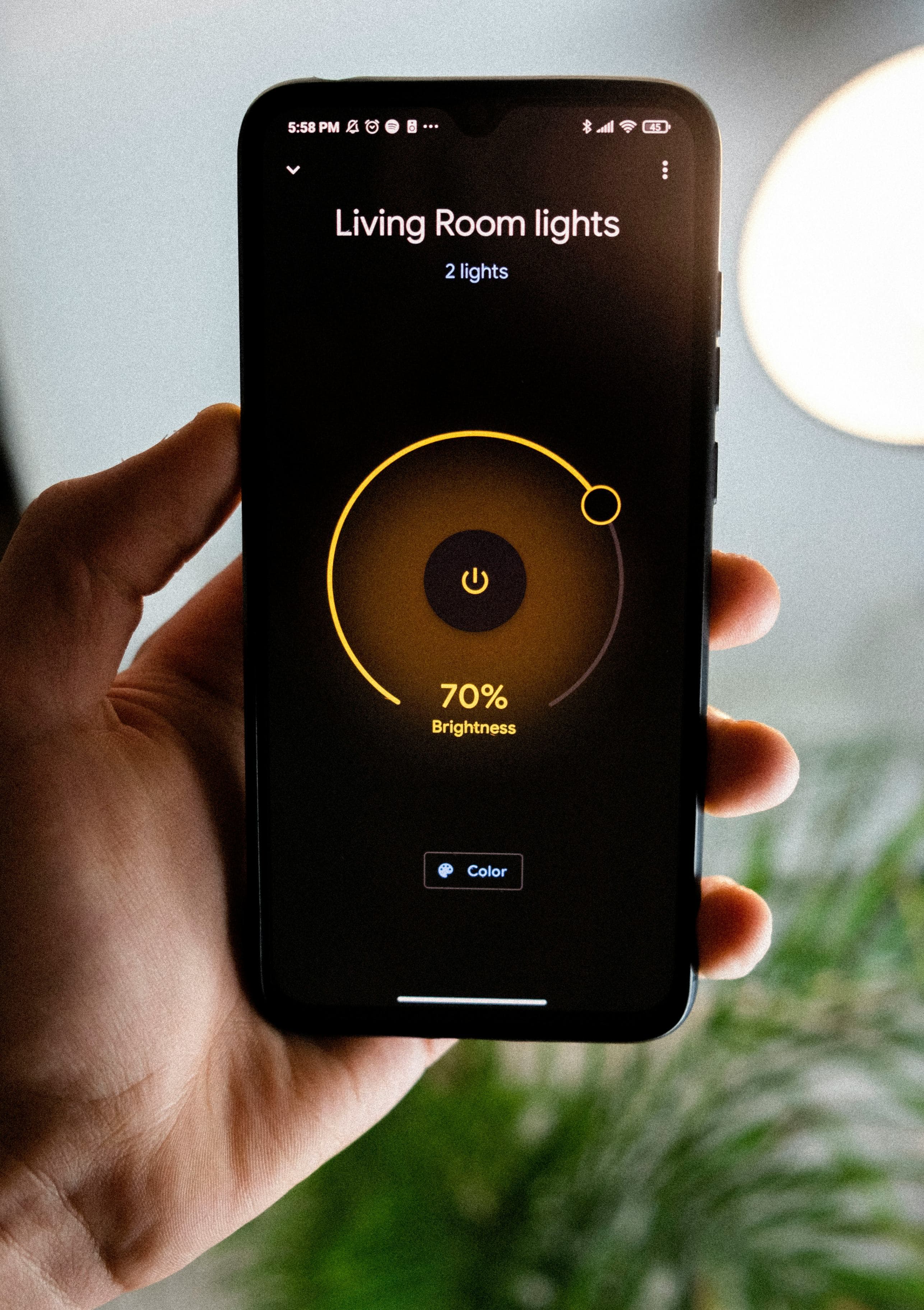 A smartphone displaying a smart home app next to a bulb and plug
